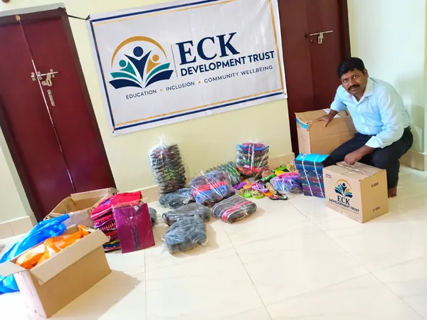 A man seated beside an assortment of materials and an ECK Development Trust banner.
