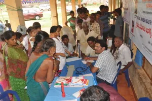 People gathered around tables for a consultation in a community hall.