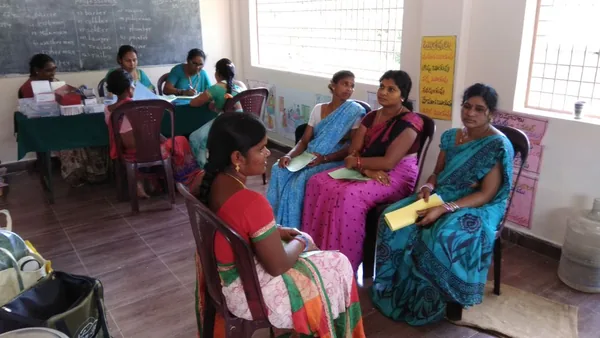 Adults seated around a table with papers in a community room.
